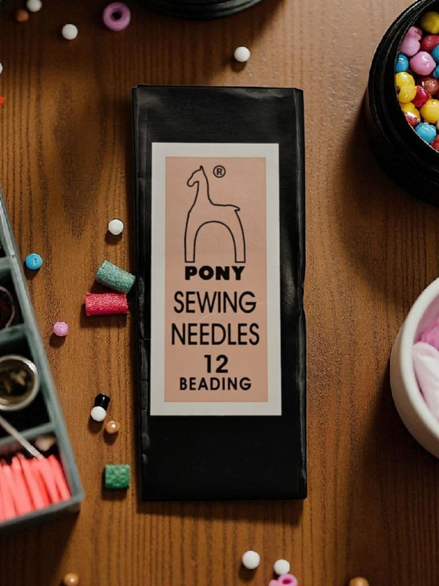 Pony Beading Needles Size 12 pack surrounded by colorful seed beads for beading projects