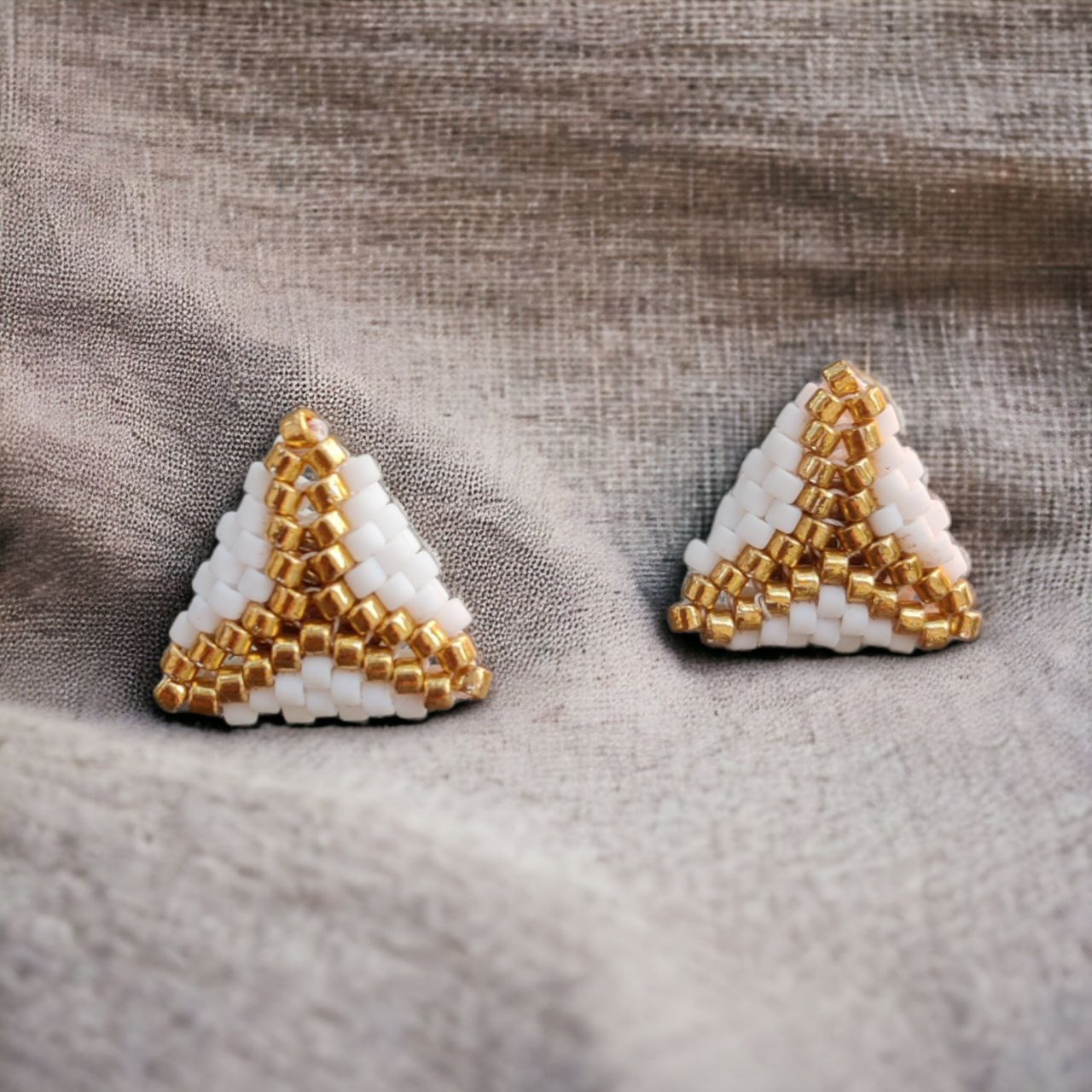 geometric white and gold seed bead stud earrings on linen fabric