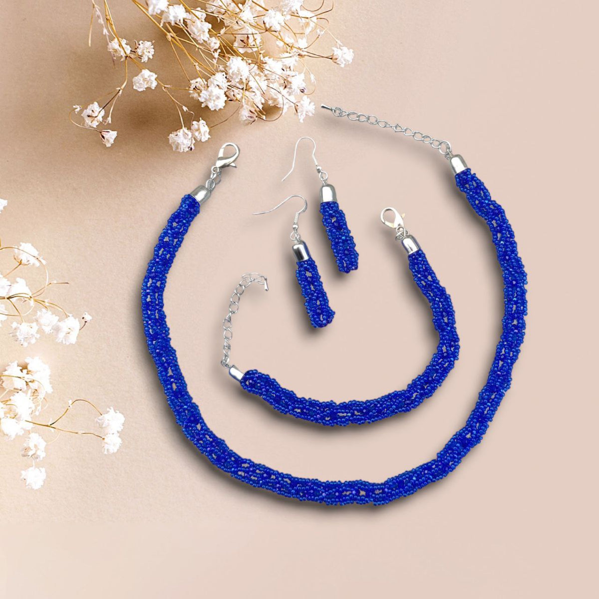 Beaded jewelry set in royal blue — necklace, bracelet and earrings on beige background