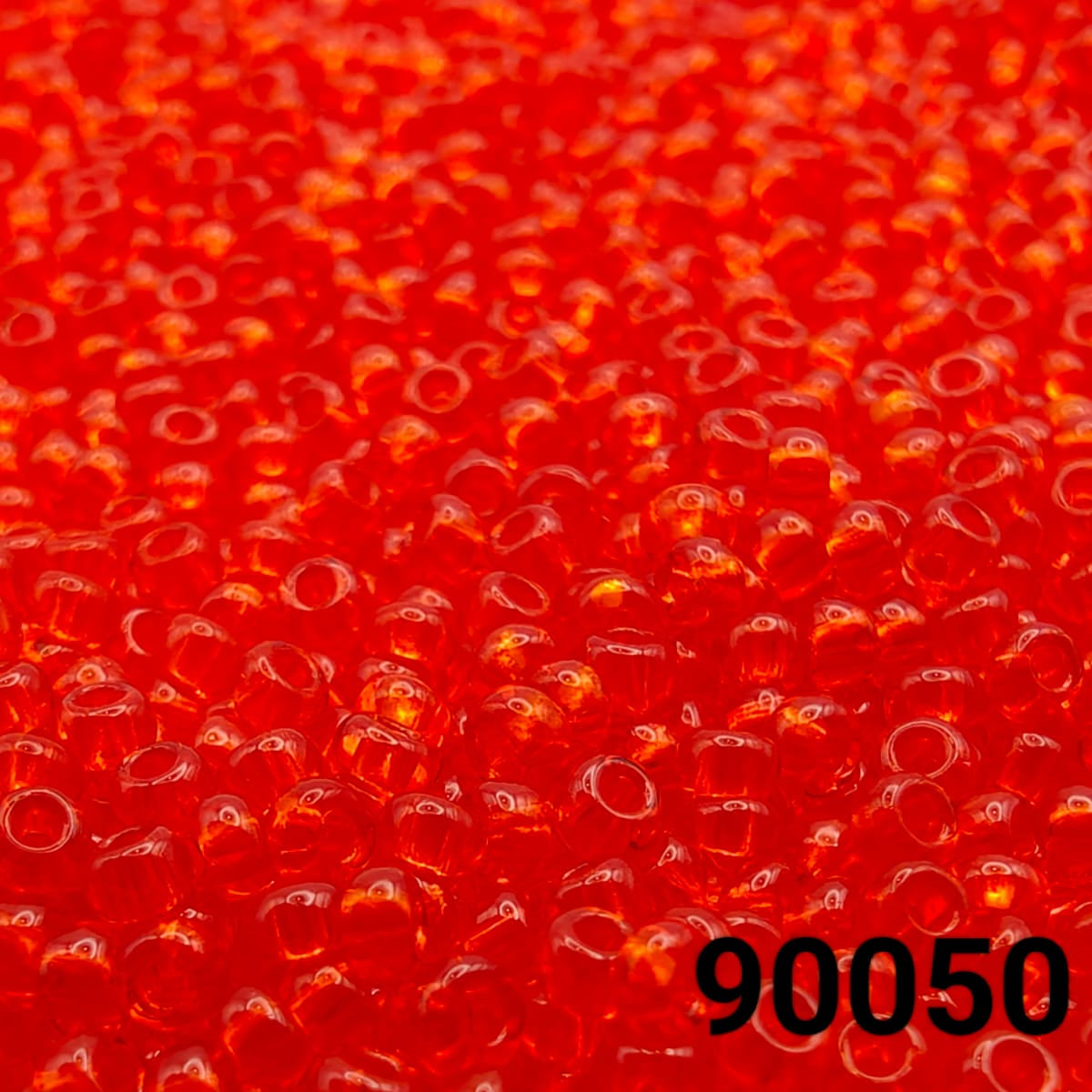 Close-up of PRECIOSA Czech 10/0 seed beads in transparent light red, colour code 90050 – round polished glass beads with smooth finish

