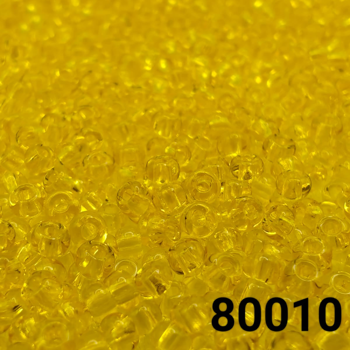 Close-up of PRECIOSA Czech seed beads 10/0 in transparent yellow, colour code 80010 – round polished glass beads
