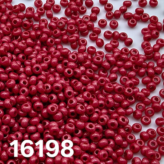 Czech seed beads 10/0 Opaque Dyed Chalk Red 16198 scattered on white.