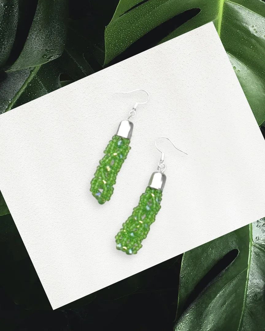 Handmade green beaded tassel earrings with silver-plated caps on white board