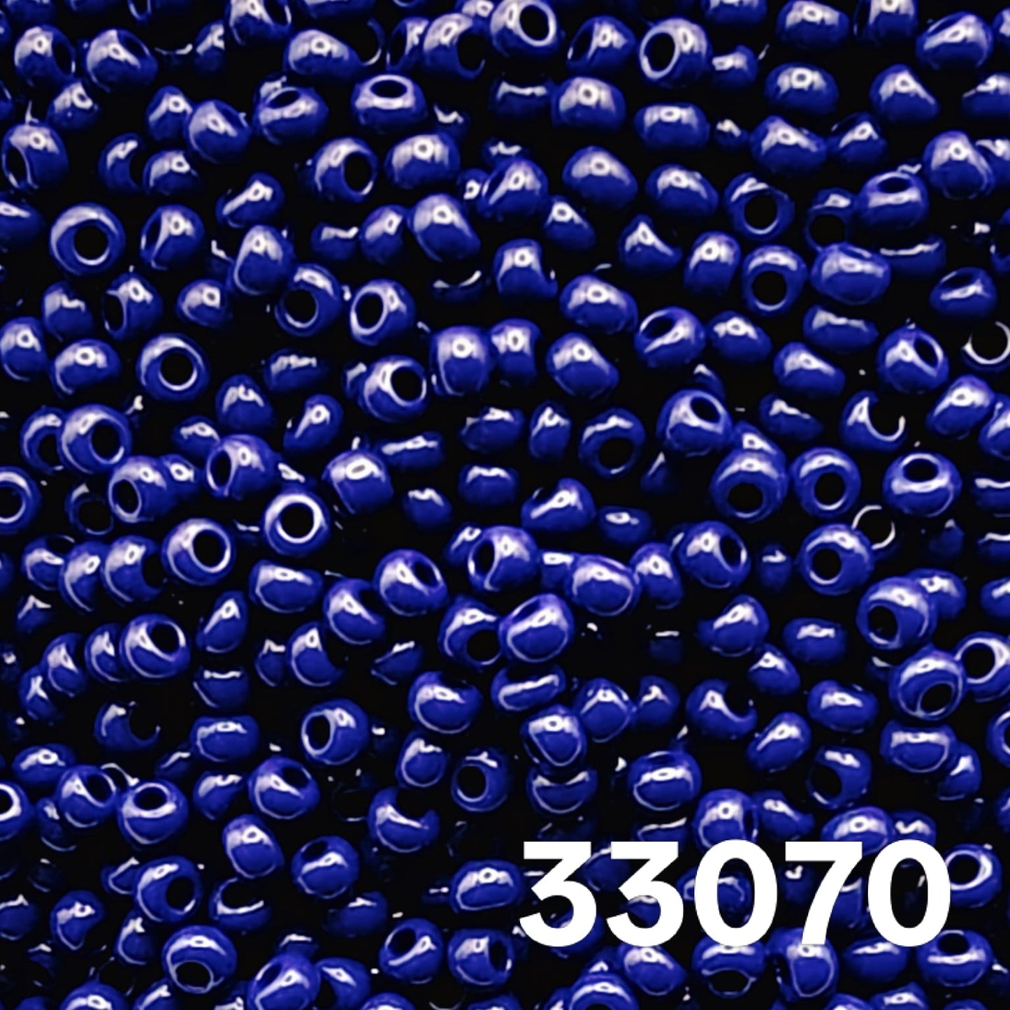 Macro close-up of Preciosa 10/0 Opaque Navy (33070) round seed beads — solid deep blue, glossy Czech glass.