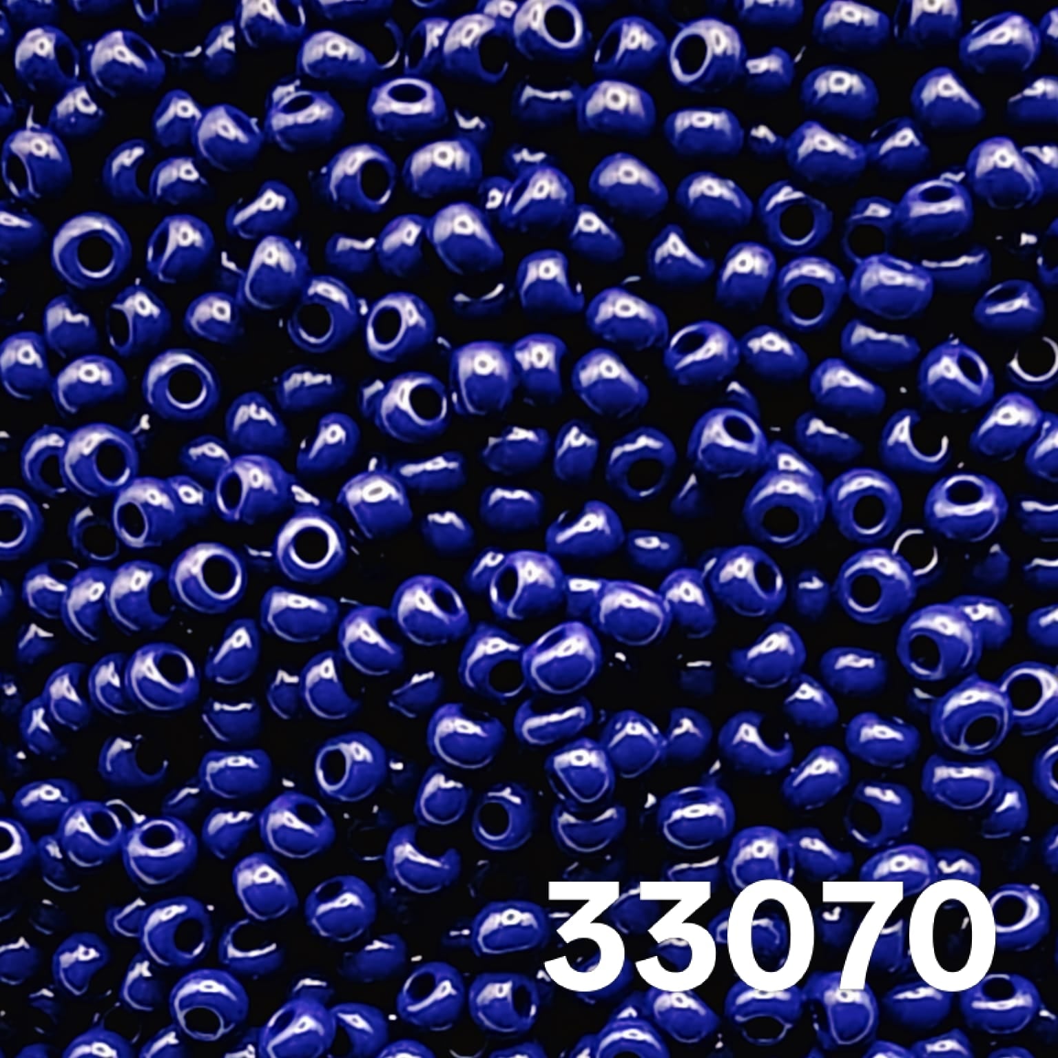 Macro close-up of Preciosa 10/0 Opaque Navy (33070) round seed beads — solid deep blue, glossy Czech glass.