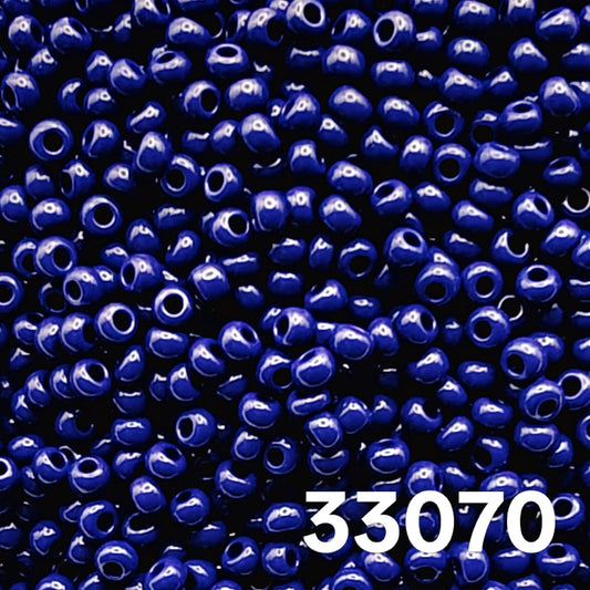 Macro close-up of Preciosa 10/0 Opaque Navy (33070) round seed beads — solid deep blue, glossy Czech glass.