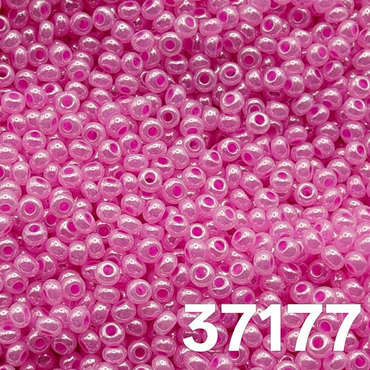 Macro close-up of Preciosa 10/0 Pearlized Ceylon Pink (37177) round seed beads — luminous candy-pink with satin ceylon luster, Czech glass.