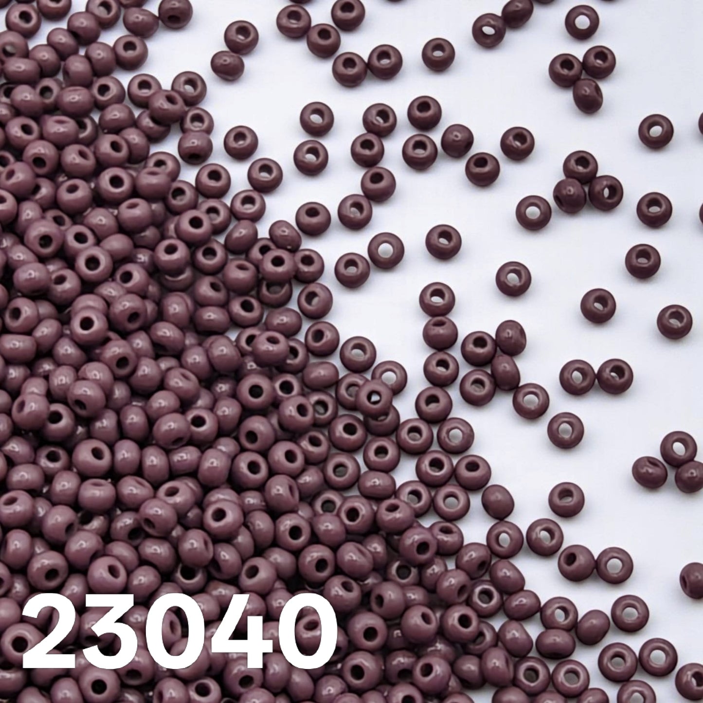 Opaque Dark Mauve Preciosa seed beads scattered on white background, size 10/0