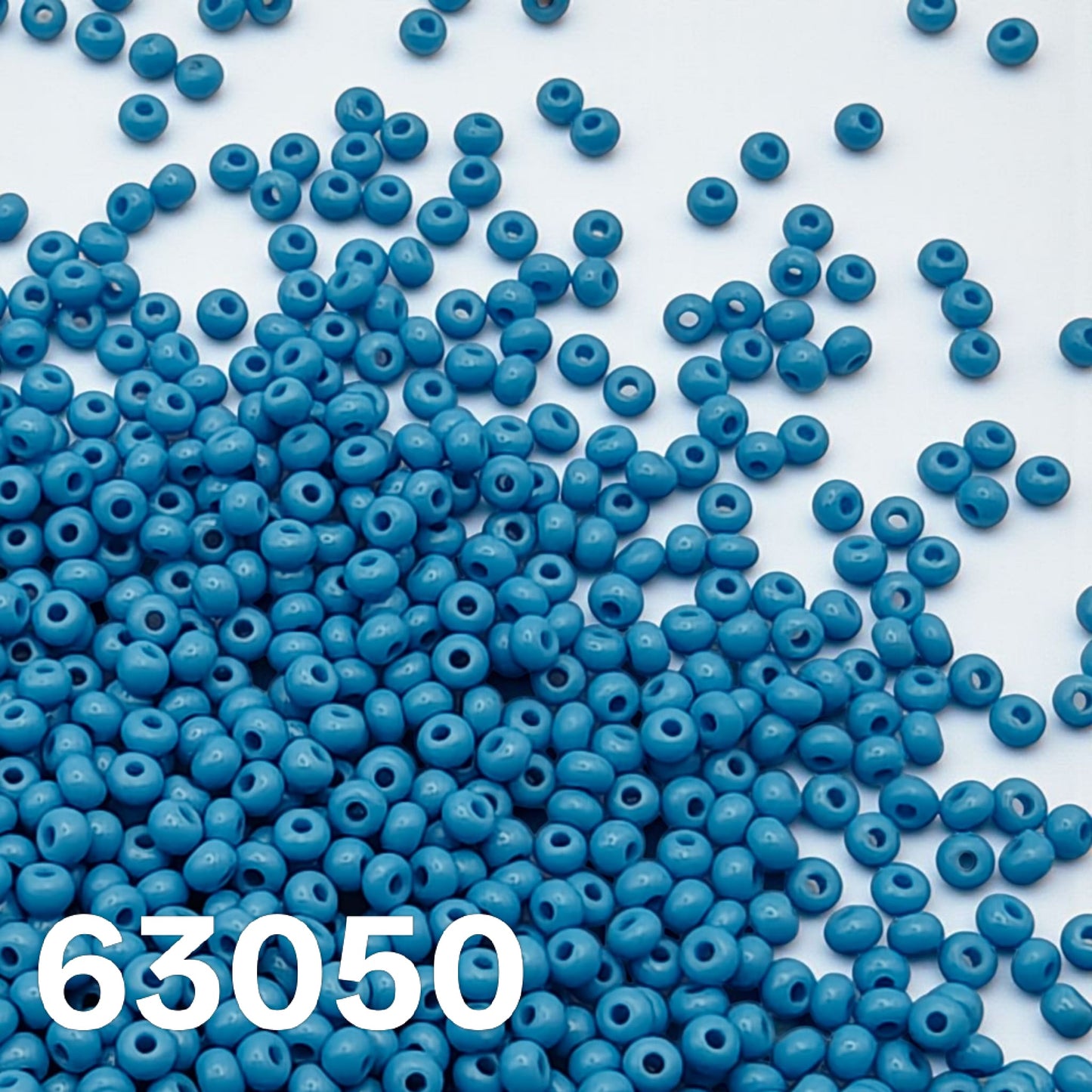 Opaque blue turquoise Czech seed beads 10/0 scattered on white background 63050