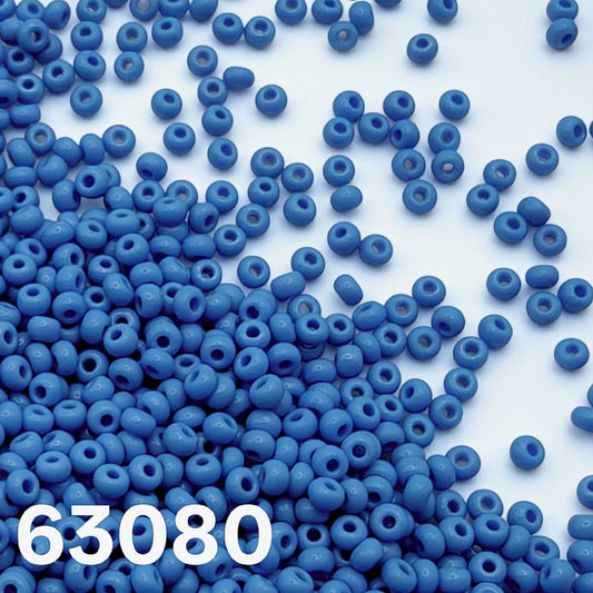 Opaque dark turquoise Czech seed beads size 10/0 63080 scattered on white surface