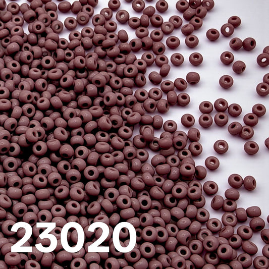 Opaque mauve 10/0 Czech seed beads 23020 scattered on white background