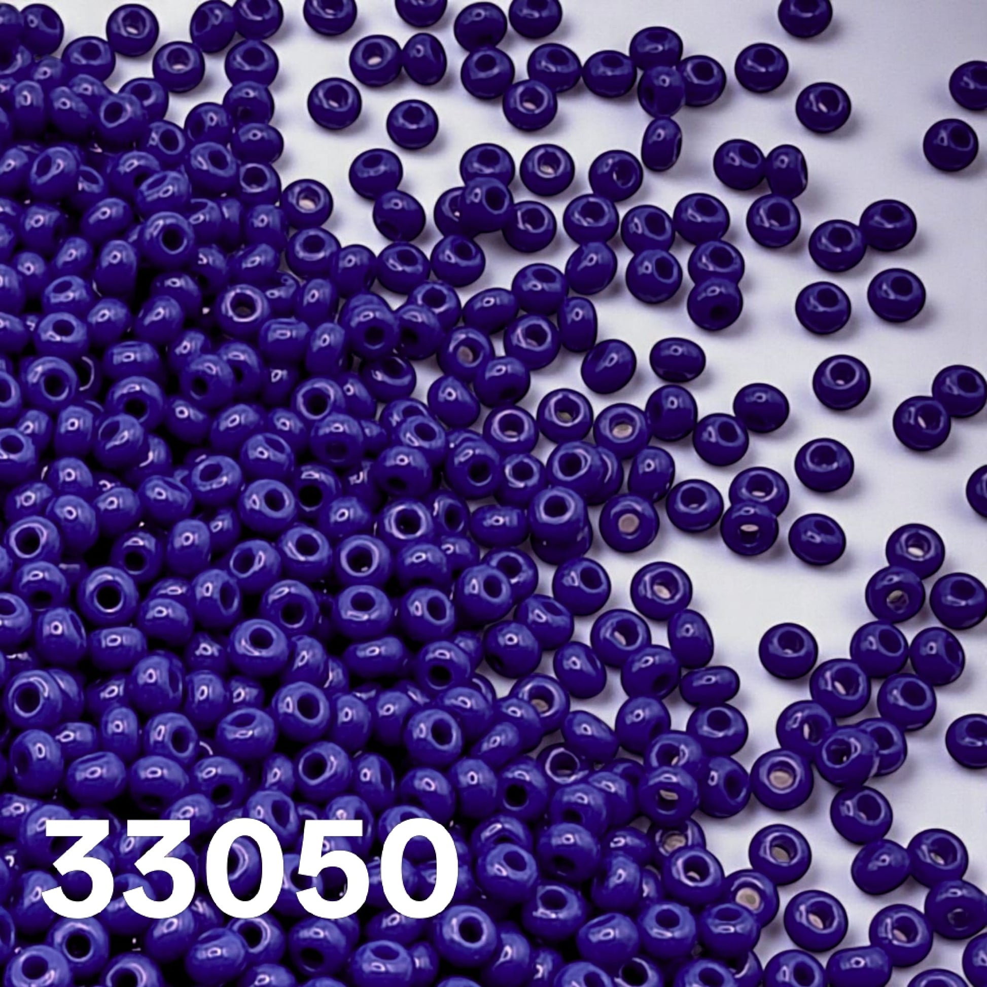 Preciosa 10/0 opaque Royal Blue seed beads 33050 scattered on white background