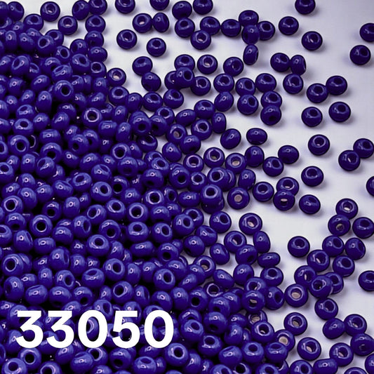 Preciosa 10/0 opaque Royal Blue seed beads 33050 scattered on white background