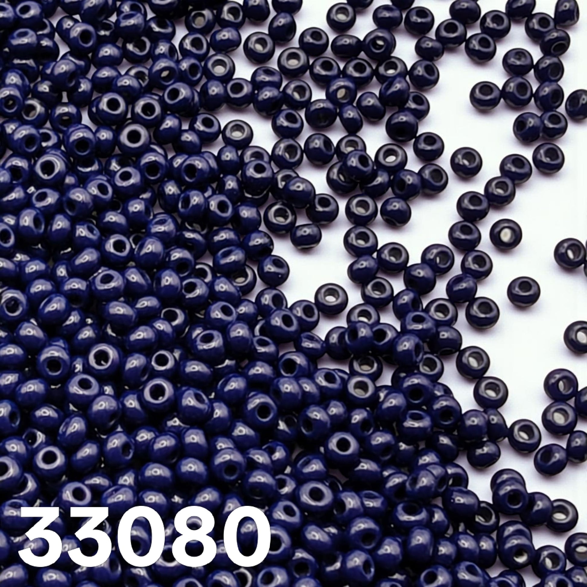Preciosa 10/0 opaque dark blue seed beads 33080 scattered on white background