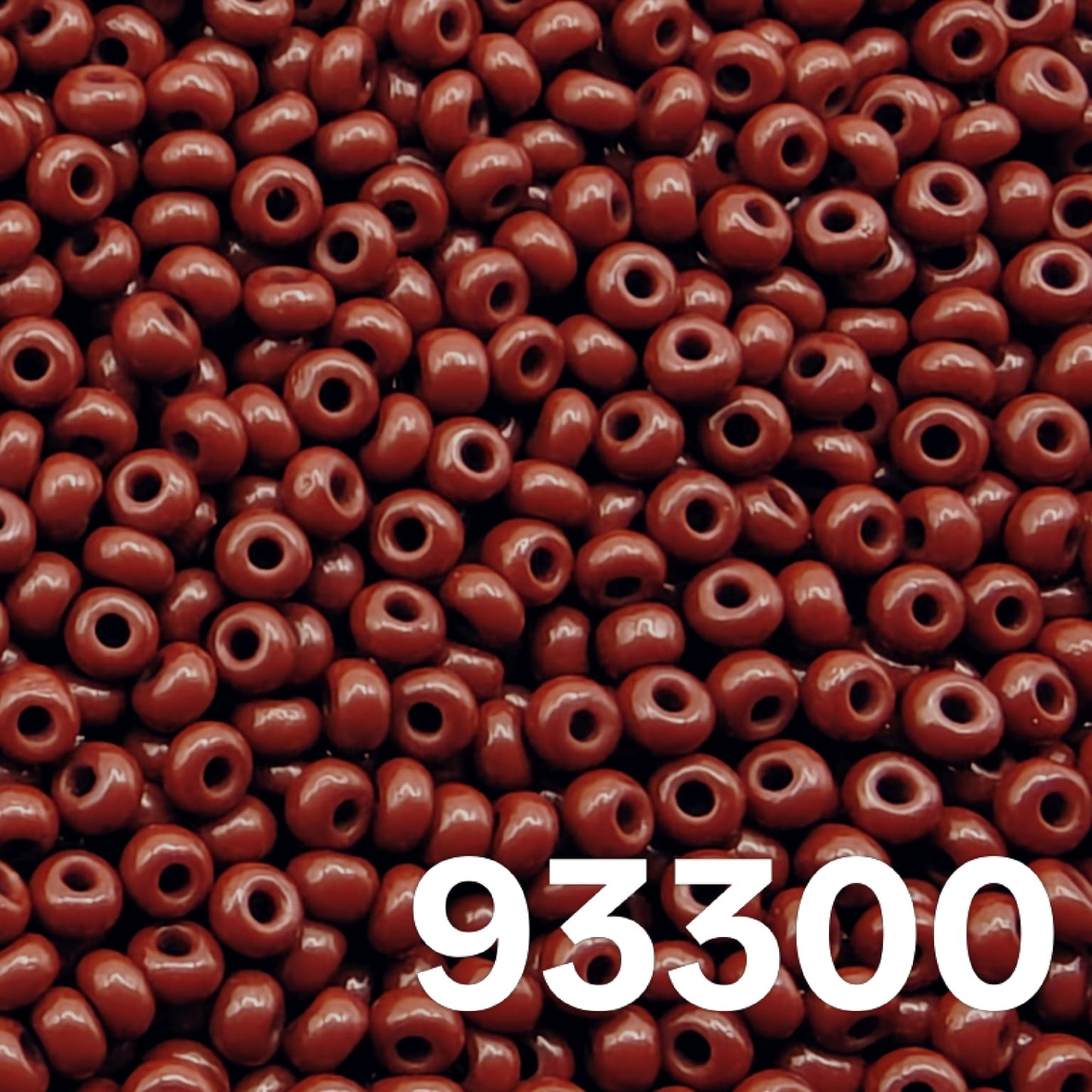 Preciosa 10/0 opaque dark red seed beads 93300 scattered on white background – close up