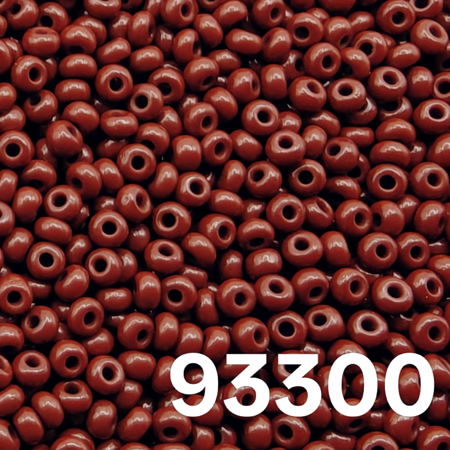 Preciosa 10/0 opaque dark red seed beads 93300 scattered on white background – close up