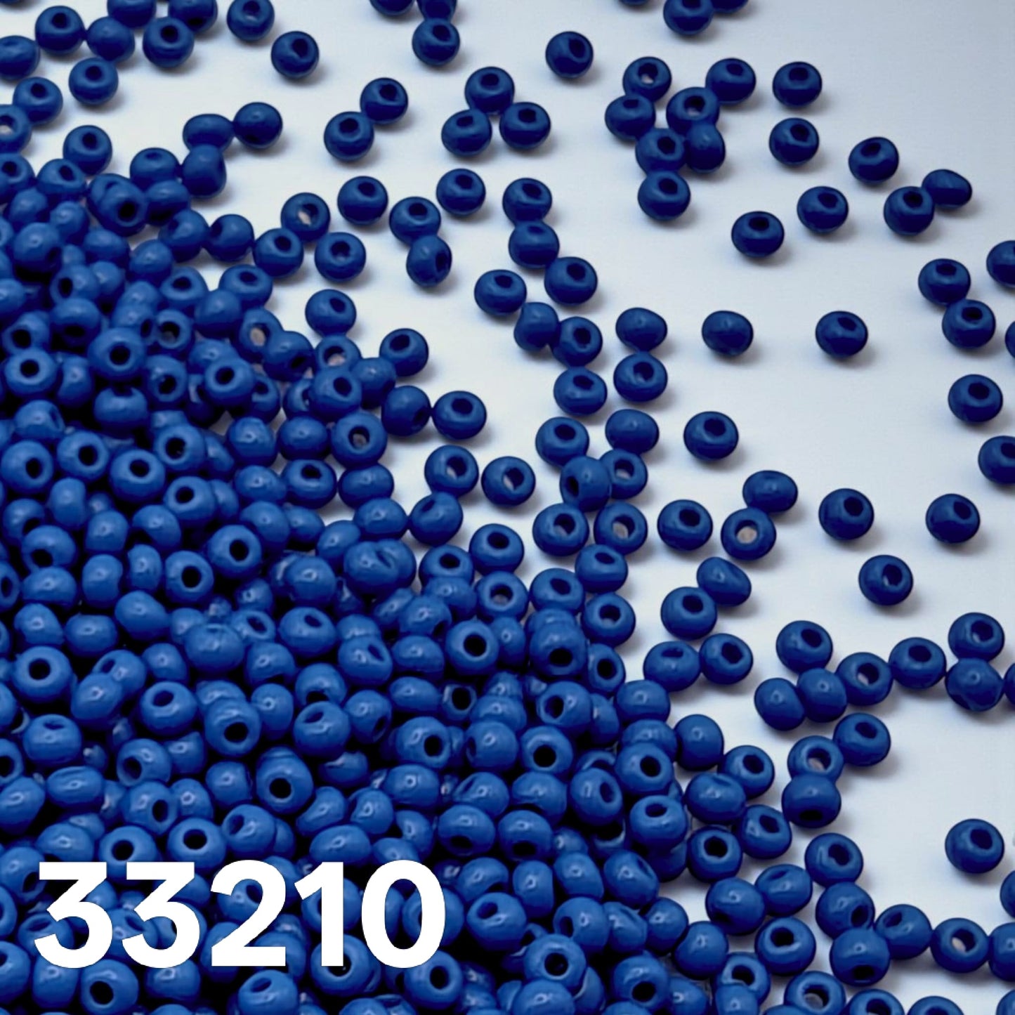 Preciosa 10/0 opaque medium blue seed beads 33210 scattered on white background