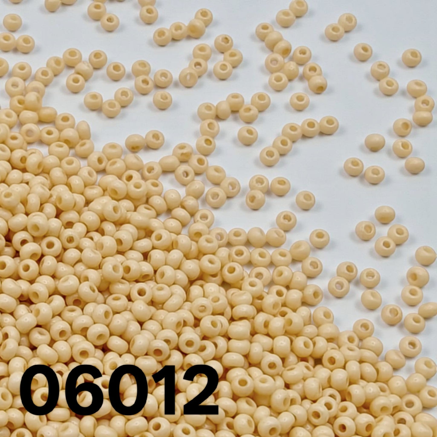 Preciosa Czech seed beads 10/0 opaque Bone 06012 scattered on a white backgroun