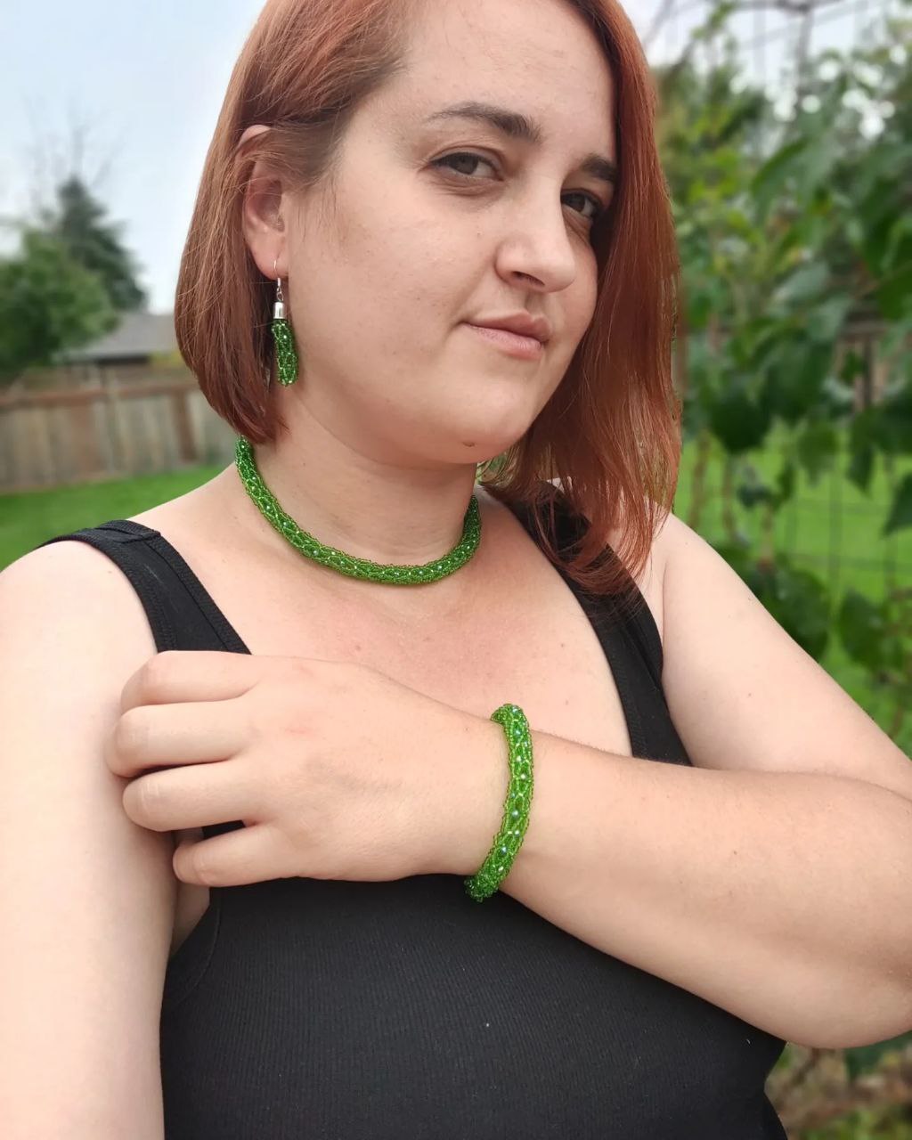 Woman wearing green beaded earrings, bracelet and choker outdoors in Canada