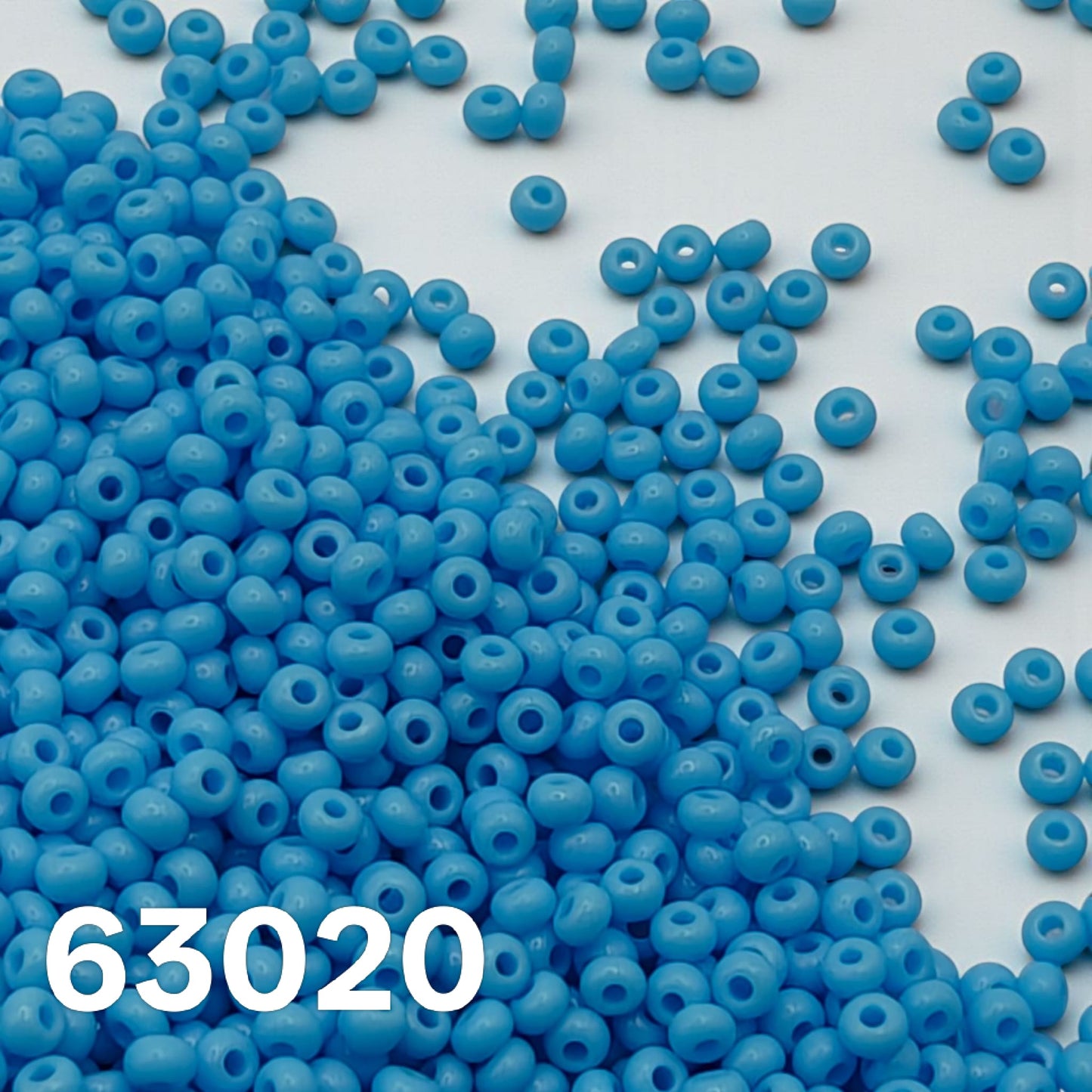 opaque light blue turquoise czech seed beads 10/0 scattered on white background 63020